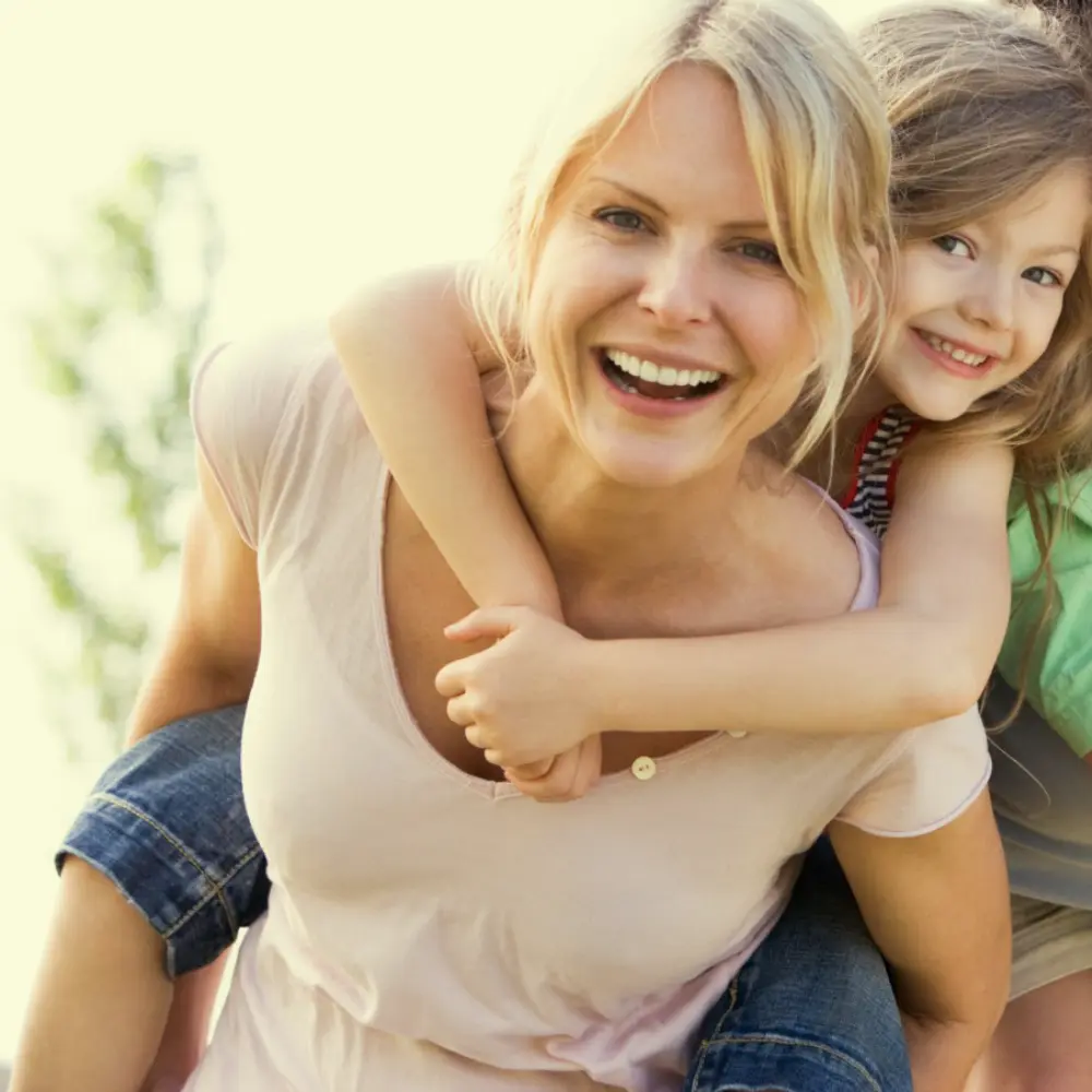 Mother with daughter on her back smiling